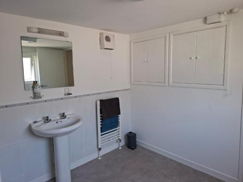a white bathroom with a sink and a mirror at 17 French Street in Teignmouth
