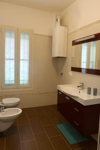 a bathroom with a sink and a toilet and a mirror at Ground floor house in Castel Bolognese
