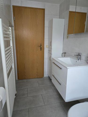 a bathroom with a sink and a wooden door at Ferienhaus Parnet in Neudorf
