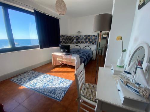 a bedroom with a bed and a desk and a window at Appartamento Teocle beach in Giardini Naxos