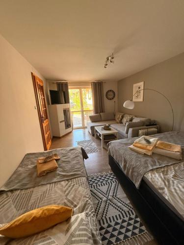 a bedroom with two beds and a living room at Sosnowe Zacisze in Zwierzyniec