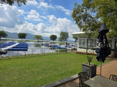 a table with an umbrella next to a river with boats at Lakeview@Pecanwood in Hartbeespoort
