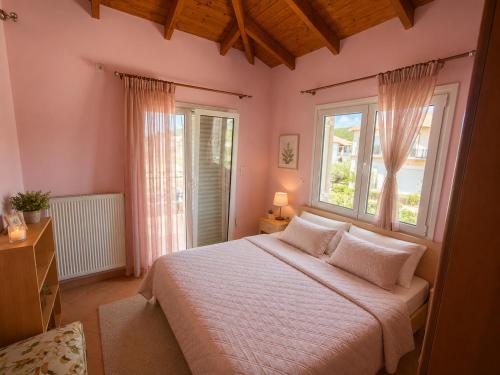 a bedroom with a large bed and two windows at Casa Rosa Ammoudia in Ammoudia