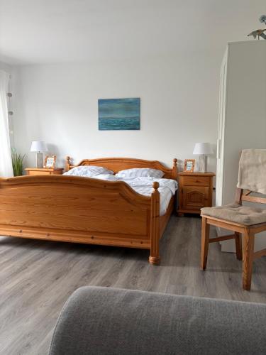 a bedroom with a wooden bed and a chair at Ferienhuus Tüütje in Wolthusen