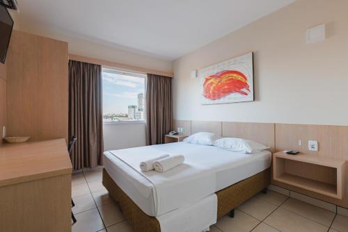 a hotel room with a bed and a window at Savana Hotel in Uberlândia