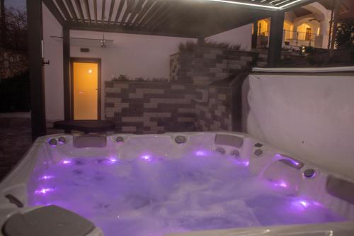 a jacuzzi tub with purple lights in a backyard at Veloralux Apartman in Kovácsszénája