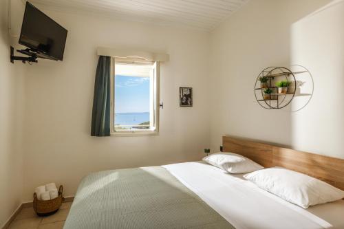a bedroom with a bed with a window and a television at Amorosa Nest - Adults Only by Eutopia in Syvota