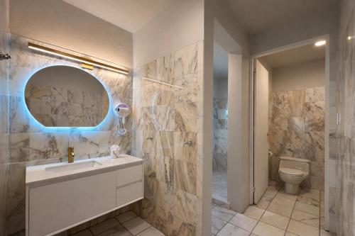 a bathroom with a sink and a toilet and a mirror at Coral Princess Hotel in San Juan