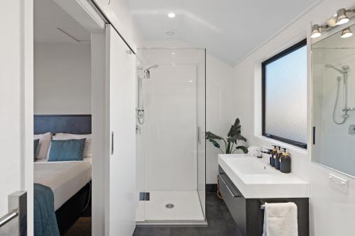 a white bathroom with a bed and a sink at Ashford Motor Lodge in Christchurch