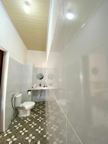 a white bathroom with a toilet and a shower at Pondok tulamben in Karangasem