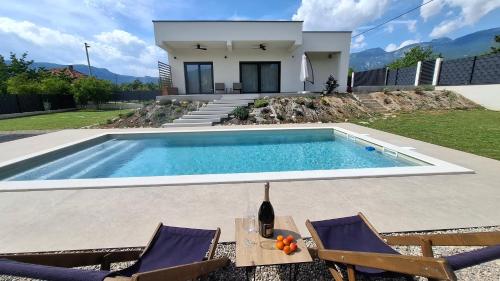 a swimming pool with two chairs and a house at Villa Velaris Mostar in Mostar