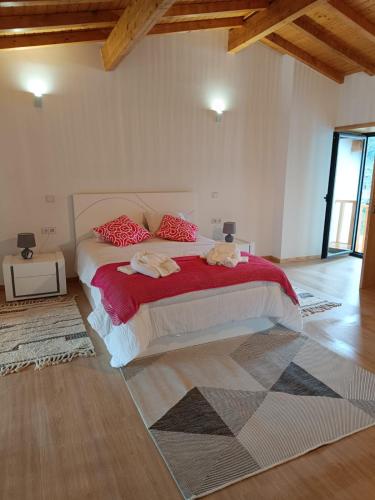 a bedroom with a large bed with red pillows at Casa da Pinha in Ponte da Barca