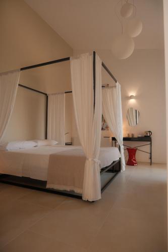 a bedroom with a canopy bed with white curtains at Nafura in Raffadali