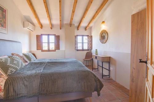 a bedroom with a bed and a desk and windows at Casa de Suenos in Comares