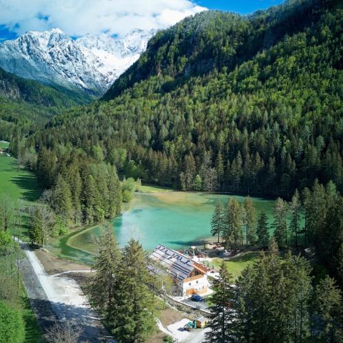a resort in the middle of a river with mountains at Gostišče Jezersko in Zgornje Jezersko