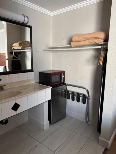 a bathroom with a sink and a microwave at Castaway Motel in Orange