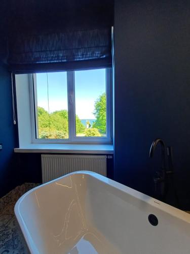 a bath tub in a bathroom with a window at Hotel Dom Marynarza in Gdynia