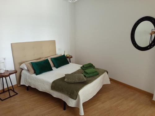a bedroom with a bed with green pillows and a mirror at VT Varadero in Fisterra