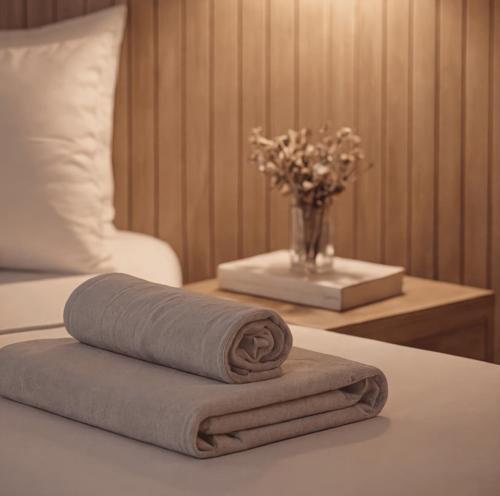 a pile of towels on a table with a vase of flowers at Bella Rose Apart Hotel, Alanya in Alanya