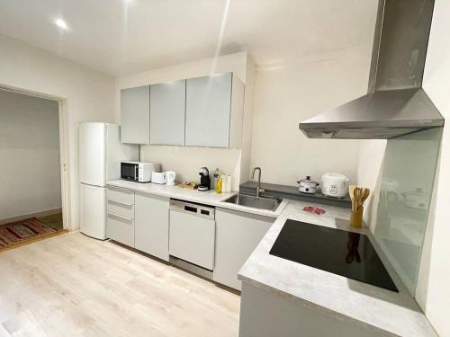 a kitchen with white cabinets and a stove top oven at Appartement Centre-ville Dole in Dole