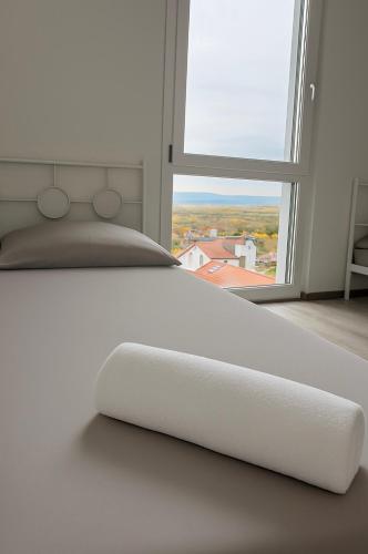 a white bed in a room with a large window at ESER - Haus am Vogesenblick in Bad Bellingen
