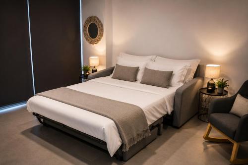 a bedroom with a large white bed and a chair at Minimal Panorama Loutraki in Loutraki