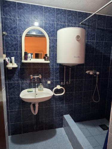 a blue tiled bathroom with a sink and a mirror at Apartmani Kruče in Ulcinj
