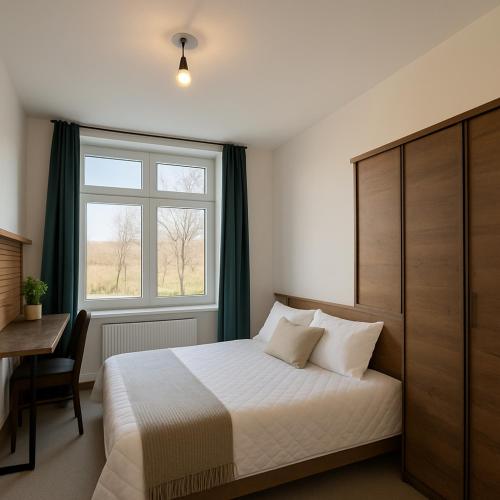 a bedroom with a bed and a window and a desk at ESER Hotel Pension in Beuggen