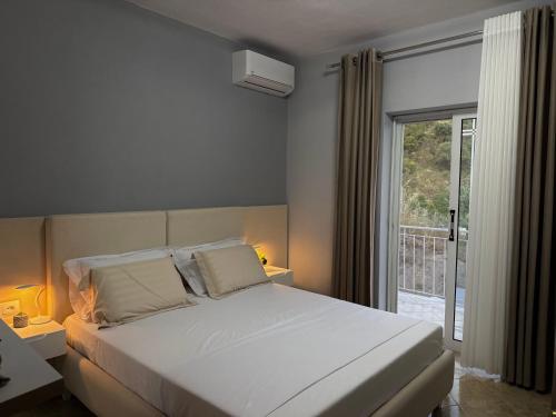 a bedroom with a white bed and a balcony at Villa Kalo in Blerimas