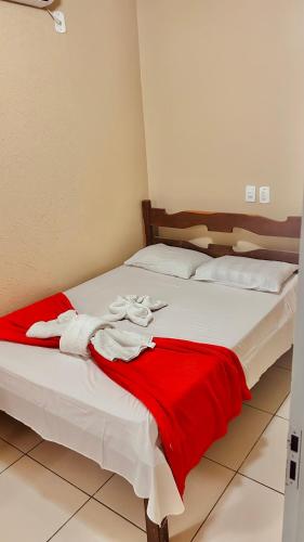 a bed with a red and white blanket on it at Pousada Paraíso in Carolina