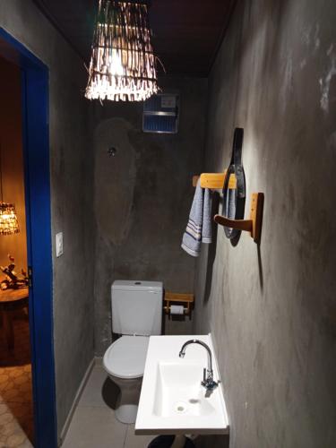 a bathroom with a sink and a toilet and a chandelier at Pousada Costa do Mar in Luis Correia