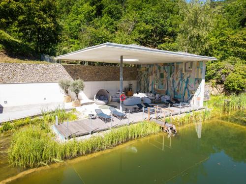 a house with a pool of water next to a lake at Nuhr Medical - Hotel & Restaurant - Ab 3 Nächten im Zeitraum vom 06 Juli bis 30 August genießen Sie pro Person eine kostenlose Massage-Unser Naturteich steht Ihnen täglich von 10 Uhr bis 18 Uhr zur Verfügung inklusive Getränke in Senftenberg