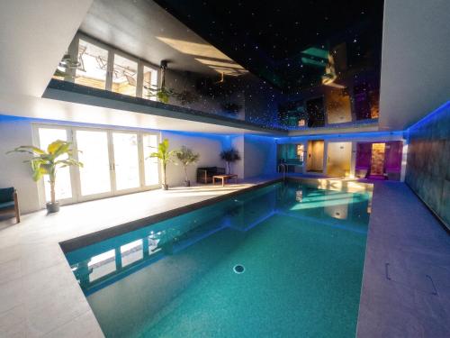 a large swimming pool in a building with blue lighting at Treloggas Retreat in Truro