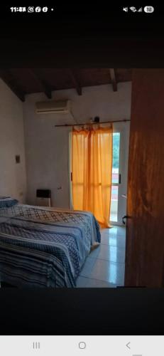 a bedroom with a bed and a window with an orange curtain at Rendel in Paraná