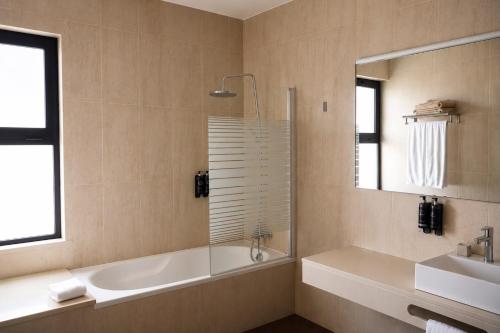 a bathroom with a tub and a sink and a mirror at Vila Foz Club - Algarve in Alvor