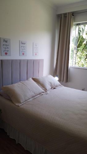 a white bed in a room with a window at Yeshua - Casa da Claudia 8 in Ilha de Guaratiba