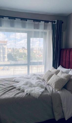 a bedroom with a bed with a large window at KHomes Luxury Bed & Breakfast in Nairobi