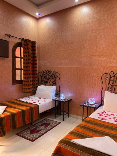 a room with two beds and two tables in it at Riad Afriquia Garden in Marrakesh