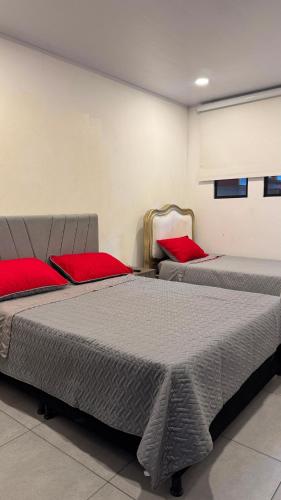 two beds in a room with red pillows at House premium in Macanal
