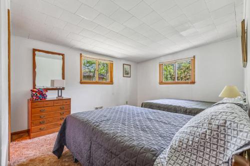 a bedroom with two beds and a dresser and two windows at Cabin #5 3BR 2BA Timberlane Resort in Park Rapids