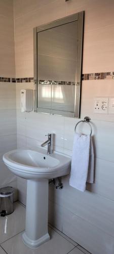 a white bathroom with a sink and a mirror at Khomasdal B&B in Windhoek
