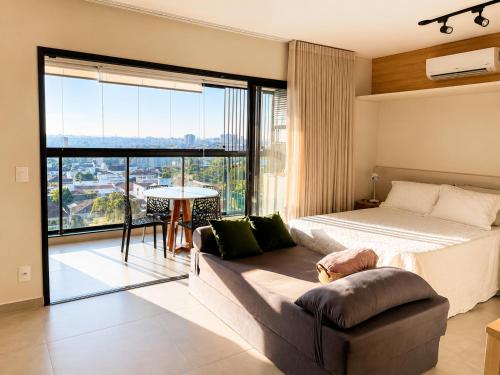 a bedroom with a bed and a couch and a large window at Studio na Av Esmeraldas com garagem in Marília