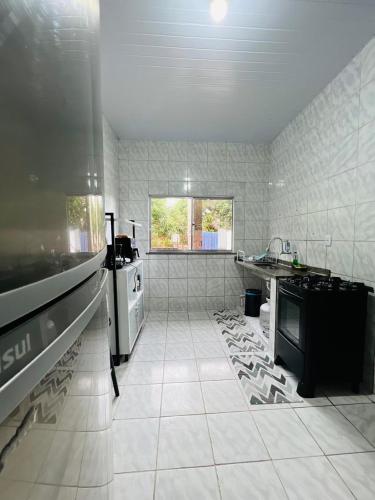 a large kitchen with white tiled floors and appliances at Recanto Tranquilo - Espaço amplo e completo - Sky in São Luís