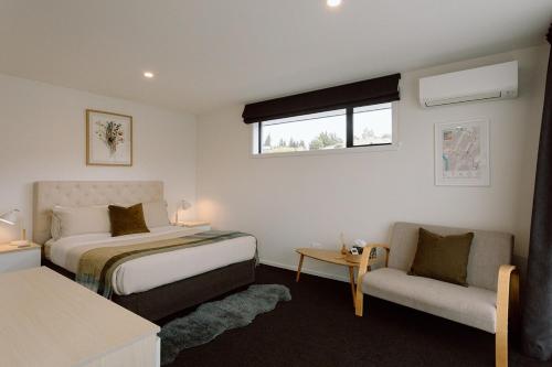 a bedroom with a bed and a couch and a window at Riverside retreat, Wanaka in Albert Town