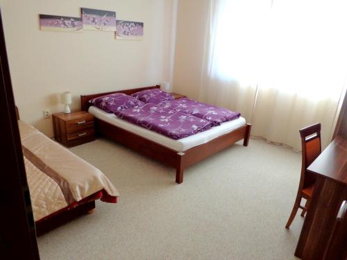 a bedroom with a bed with purple sheets and a window at Penzión Reduta in Oravský Podzámok