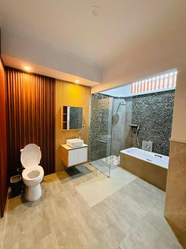 a bathroom with a toilet and a sink and a tub at MEDEWI BREEZE House in Airsatang