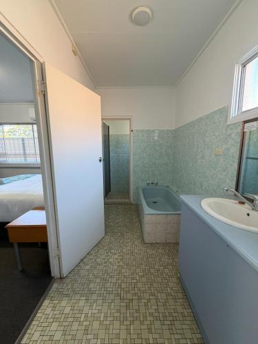 a bathroom with a tub and a sink and a bath tub at Riviera Motel Bundaberg in Bundaberg
