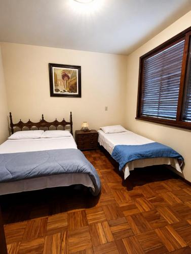 two beds in a bedroom with wooden floors and a window at Suíte Pimenteiras in Teresópolis