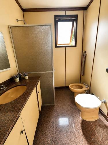 a bathroom with a toilet and a sink and a shower at Suíte Pimenteiras in Teresópolis