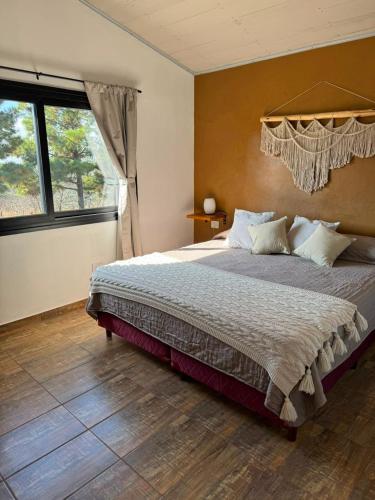 a bedroom with a large bed and a window at Crisálida Cabañas Villa Yacanto in Villa Yacanto